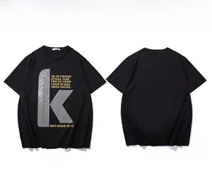 Détails du t-shirt noir oversize avec logo K en paillettes argentées et motifs dorés