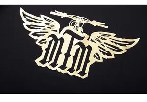 Detailed close-up of golden FREE RIDERS print on black cotton fabric texture