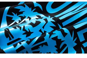 Close-up of bright cyan palm tree and letter print on black cotton fabric texture