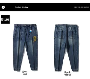 Detail of blue denim joggers featuring elastic drawstring waist and gold embroidery