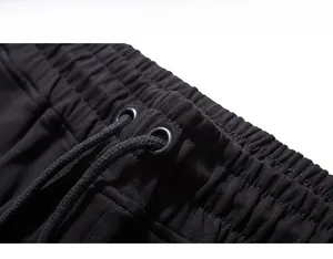 Detail of men's sweatpants featuring elastic waistband with drawstrings and metal eyelets