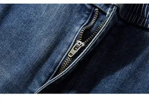 Close-up of premium YKK brass zipper on washed dark blue stretch denim pants fabric
