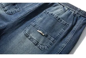 Detail of deep blue men's denim jogger with elastic waistband and woven logo tag