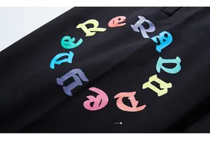Detail of street-style black jogger pants featuring colorful neon gradient gothic print