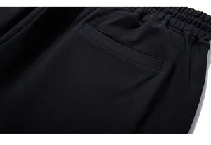 Macro detail of high-quality black cotton joggers with yellow logo and elastic waistband