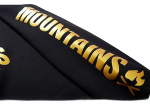 Detail of sweatshirt sleeve showing gold foil mountains print on black knitted fabric