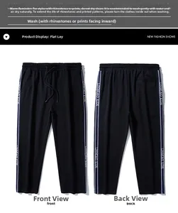 Detail of black sports trousers with side tape stripes and elastic drawstring waistband