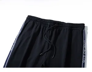 Detail view of black athletic pants with drawstring waist and side lettered webbing
