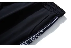 Macro detail of elastic waistband and side letter-patterned ribbon on black joggers