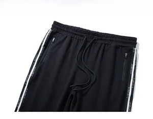 Close-up of elastic waistband with drawstring and zippered pockets on black sports joggers