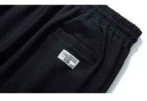 Detail of black sports trousers featuring an elastic waistband and a branded back pocket label