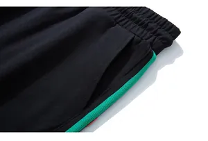 Dettaglio dei pantaloni sportivi neri con strisce laterali verde neon e vita elastica