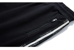 Detail of black sports trousers featuring a zip pocket and branded woven side tape