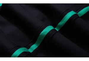 Dettaglio macro dei pantaloni sportivi neri con strisce verdi in tessuto e trama nitida