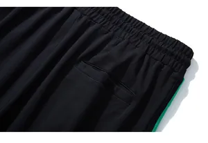 Dettaglio della vita elastica e banda laterale verde sui pantaloni sportivi neri