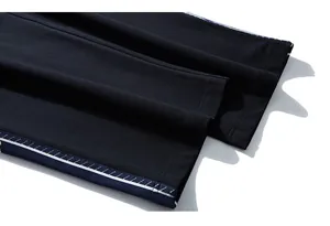 Detail of navy blue side stripe with white dotted print on black knit sports pants