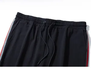 Detail of black sports sweatpants featuring elastic waist with drawstring and side stripes