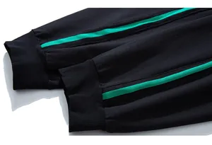 Dettaglio dei pantaloni sportivi neri con polsini a coste e strisce laterali verdi