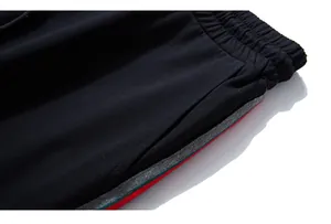 Detailed view of elastic waistband and tricolor side stripes on black joggers