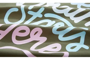 Macro detail of olive green knit fabric with colorful graffiti puffed print patterns