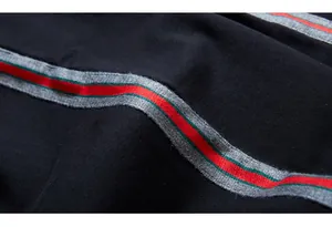 Detail shot of the side stripe on black joggers featuring red and green webbing pattern