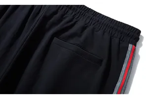 Detail of black sports pants featuring an elastic waistband and iconic striped side ribbon