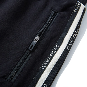 Men's black joggers featuring side stripe webbing and secure metal zipper pockets