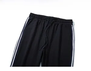 Détail d'un pantalon de sport noir avec taille élastique à cordon et bandes latérales