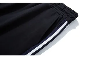 Détail de la taille du jogging noir avec cordon élastique et bandes latérales bleues