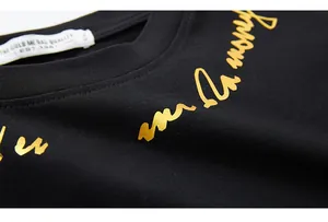 Détail macro de l'impression à la feuille d'or et de l'encolure sur un t-shirt en coton noir