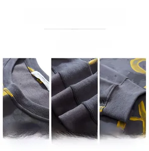 Detailed view of grey sweatshirt crewneck, flat-stitched seams and ribbed cuffs with yellow print