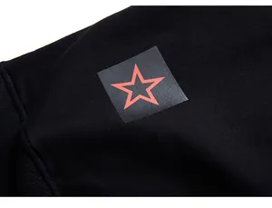Close-up of a square patch print with a red star on a black cotton sweatshirt sleeve