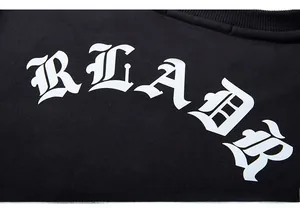 Détail du lettrage gothique blanc READR imprimé sur un sweat-shirt en coton noir de qualité