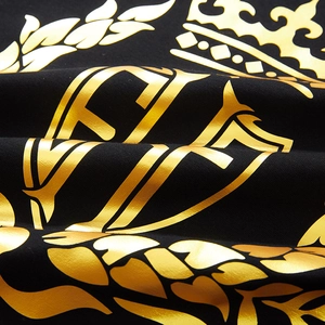 Primo piano di una t-shirt nera con stampa di corona e scudo in lamina d'oro premium