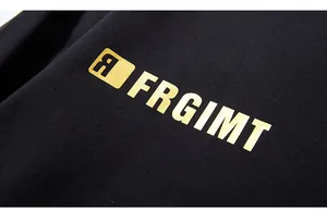 Detail shot of metallic gold FRGIMT lettering and logo on black cotton sweatshirt fabric