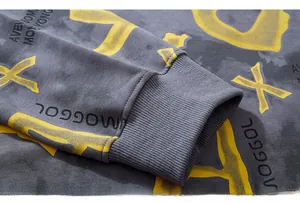 Close-up of ribbed cuffs on gray sweatshirt featuring yellow graffiti letter printing