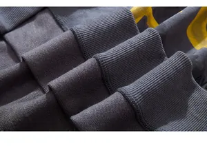 Macro shot of thick ribbed cuffs and high-quality yellow graphic print on dark gray sweatshirt