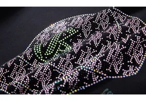 Close-up of sparkling pink and green rhinestones on black streetwear hoodie fabric