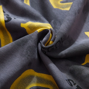 Close-up of oversized sweatshirt with yellow abstract print and black lettering on gray fabric