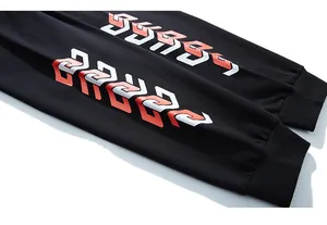 Detail of black sports trousers with red and white geometric prints and ribbed ankle cuffs