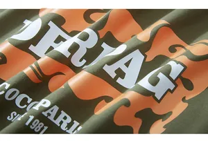 Détail du tissu olive avec imprimés ondulés orange et lettrage blanc de style vintage