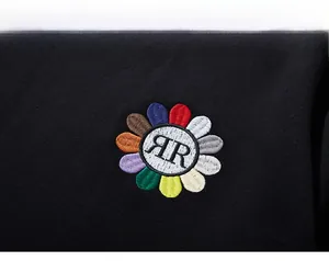 Detailed close-up of vibrant floral embroidery with RR letters on black cotton sweatshirt