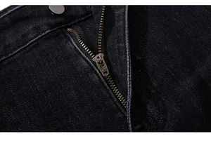 Detail of YKK metal zipper and grey button on black denim trousers with twill texture