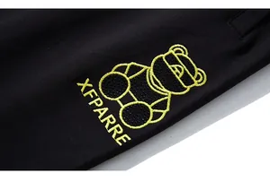 Broderie ours jaune et lettrage XFPARRE sur le tissu en maille noire du jogging