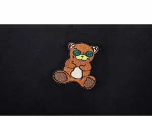 Close-up of premium bear embroidery patch with green X eyes on black sweatshirt