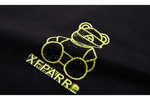 Détail de la broderie d'ours jaune et strass noirs sur le pantalon de jogging homme