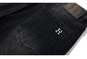 Detail of dark wash denim jeans showing vintage leather patch and H embroidery on pocket