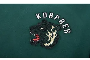 Gros plan détaillé de la broderie tête de tigre sur un sweat-shirt vert foncé