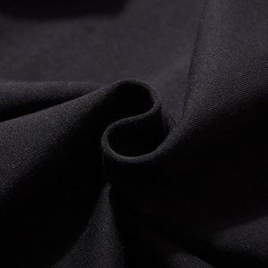 Gros plan sur la texture du tissu en maille noire du pantalon de jogging brodé ours