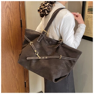 Detail of dark brown suede tote bag with white stitching and gold hardware on shoulder